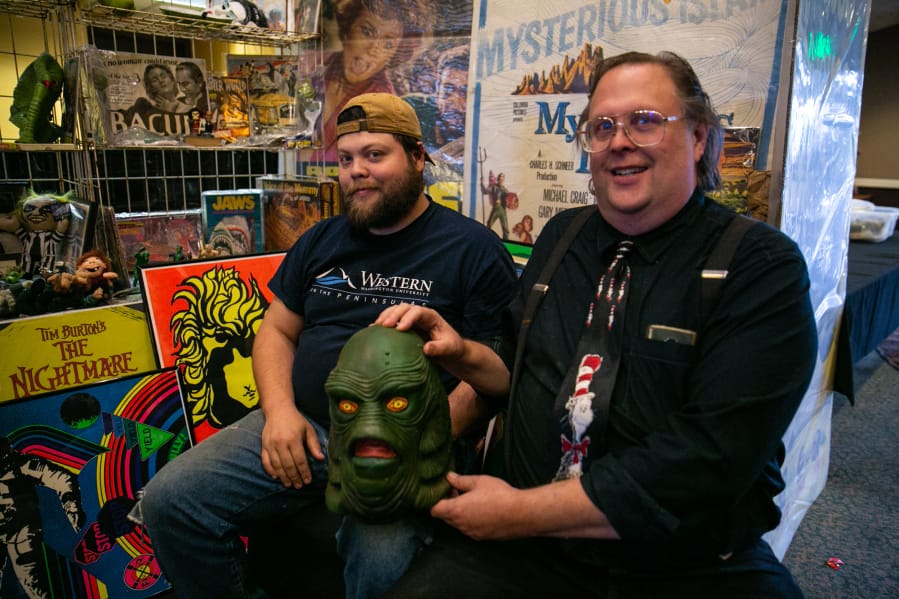 Corey Mallonèe, left, and his dad, Art Mallonèe, of Port Orchard pose with The Creature from the Black Lagoon at their booth Sunday afternoon at the Vancouver Toy Junkies Vintage Toy Show and Sale at WareHouse '23.