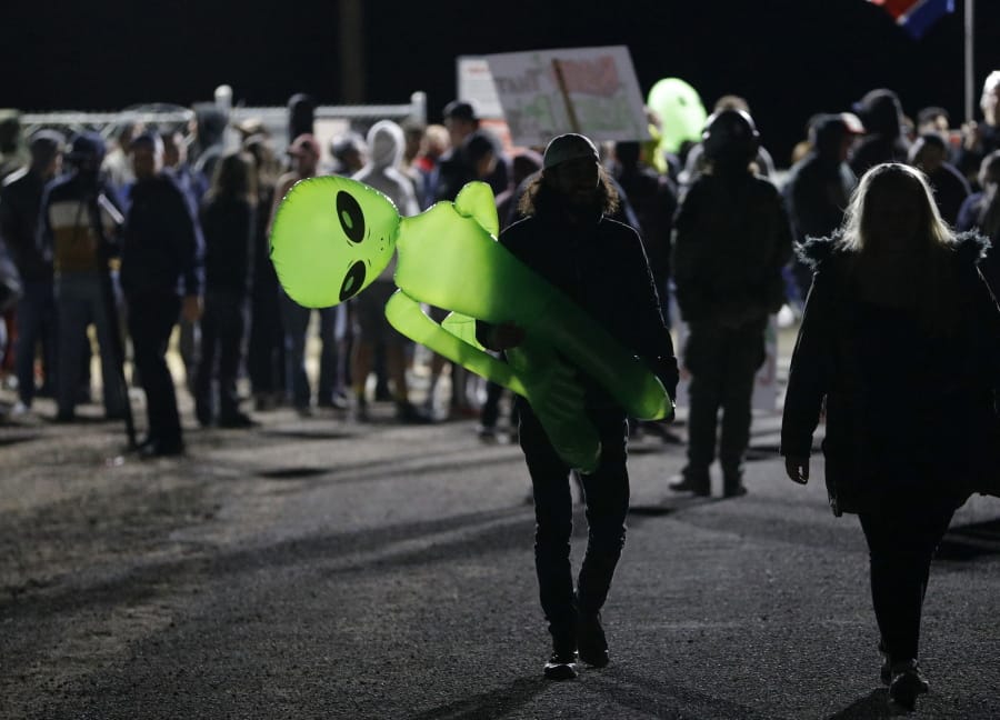 A mans holds an inflatable alien at an entrance to the Nevada Test and Training Range near Area 51 Friday, Sept. 20, 2019, near Rachel, Nev. People gathered at the gate inspired by the &quot;Storm Area 51&quot; internet hoax.