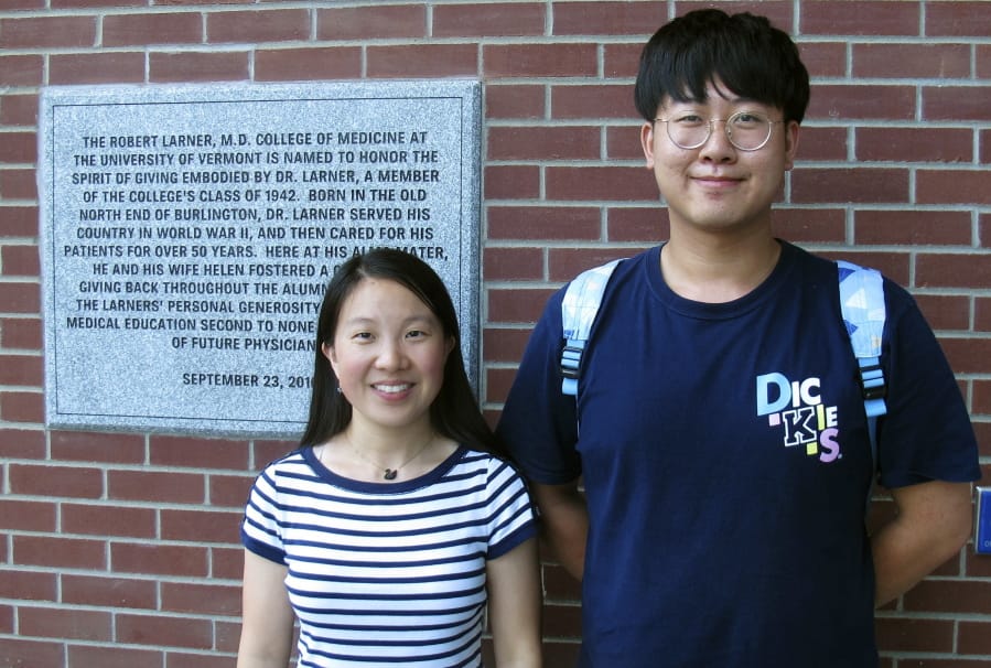 In this photo Aug. 16, 2019, photo, Chinese graduate students Zhaojin Li, left, and Pengfei Liu, pose in front of the entrance to the Robert Larner College of Medicine at the University of Vermont in Burlington, Vt. Some higher education officials are concerned by a drop in the number of international students coming to the United States, especially from China. Li and Liu say that some of their relatives were concerned for their safety in coming to the United States, but they are too busy with their studies to focus on geopolitical issues.