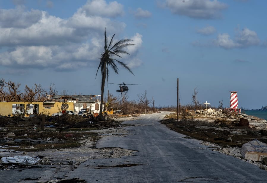 A helicopter flies over the village of High Rock after delivering emergency supplies in the aftermath of Hurricane Dorian In High Rock, Grand Bahama, Bahamas, Tuesday, September 10, 2019.