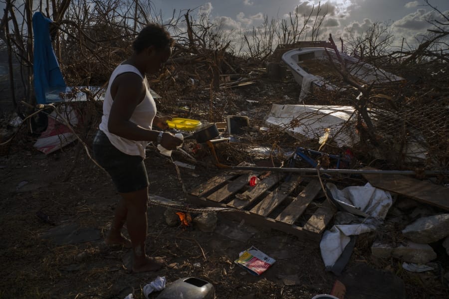 Tereha Davis, 45, holds a plate of rice as she walks among the remains of her shattered belongings, in the aftermath of Hurricane Dorian, in McLean’s Town, Grand Bahama, Bahamas, Wednesday Sept. 11, 2019. She and others said they had not seen any government officials and have only received food and water from some nonprofit organizations.