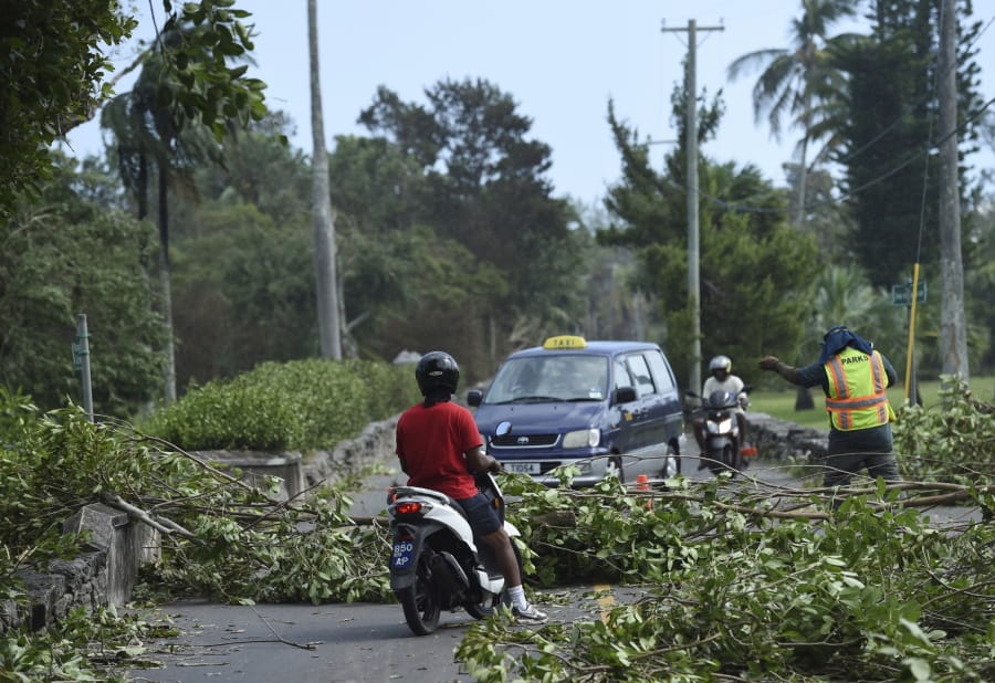 A city worker directs traffic Thursday away from trees felled by Hurricane Humberto in the Devonshire parish of Bermuda. (Akil J.