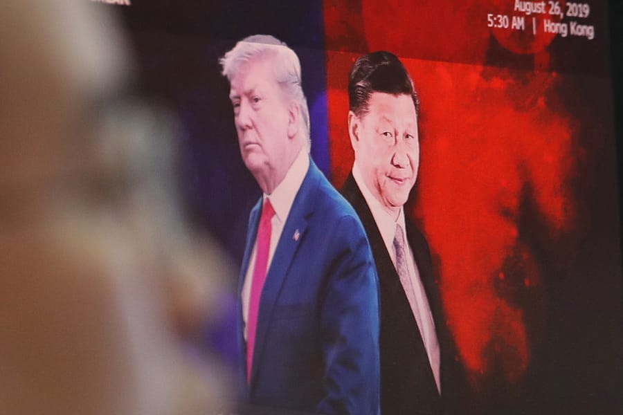 FIEL - In this Aug. 26, 2019, file photo, a computer screen shows images of Chinese President Xi Jinping, right, and U.S. President Donald Trump as a currency trader works at the foreign exchange dealing room of the KEB Hana Bank headquarters in Seoul, South Korea. China will lift punitive tariffs imposed on U.S. soybeans and pork in a trade war with Washington, a state news agency said Friday, Sept. 13, 2019, in a possible goodwill gesture ahead of negotiations.