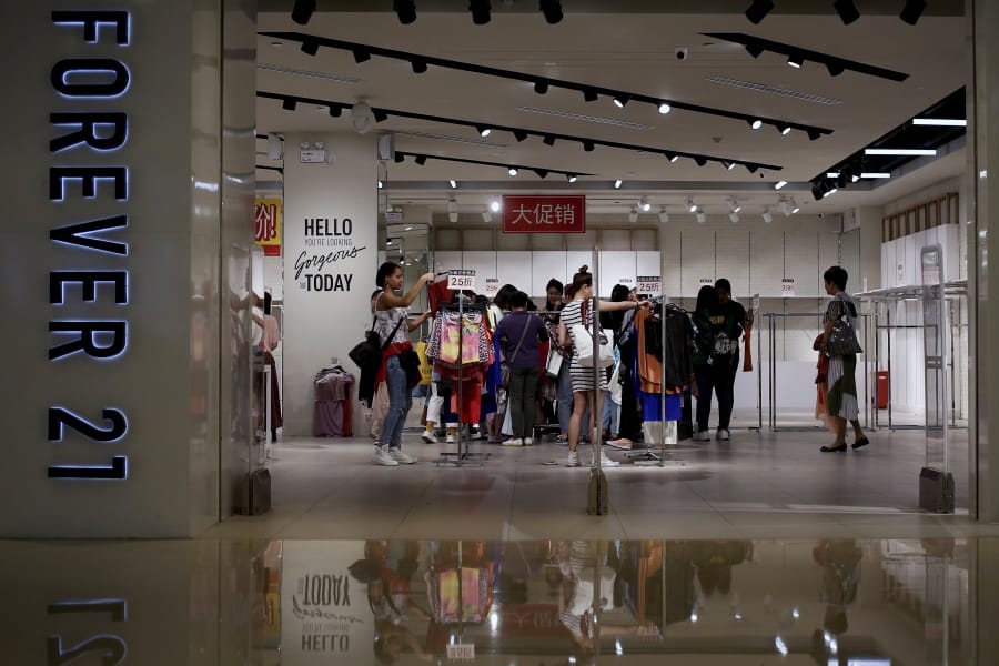 FILE - In this Tuesday, May 7, 2019, file photo, women select clothing at an American fast fashion retailer Forever 21 which is offering clearance discounts at a shopping mall after it pulled out from China&#039;s market, in Beijing. Low-price fashion chain Forever 21, a one-time hot destination for teen shoppers that fell victim of its own rapid expansion and changing consumer tastes, announced Sunday, Sept. 29, 2019, that it has filed for Chapter 11 bankruptcy protection.