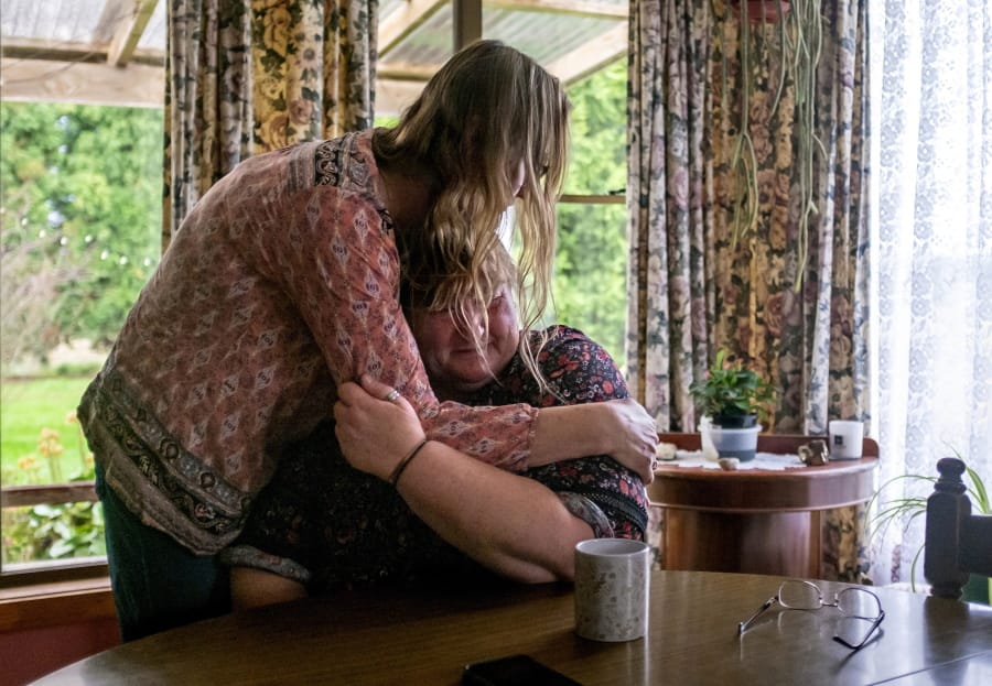Carmall Casey, right, is embraced by Maxine Piper, a longtime friend and a source of support through Casey’s addiction to opioids and battle with chronic pain, at her home in Black River, Tasmania, Australia, Tuesday, July 23, 2019. Casey doesn’t know what she’ll do when the pain returns. But she says she will never return to opioids. “I’m not going back,” she says and begins to weep.