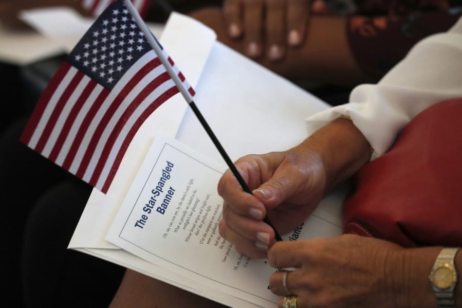 FILE - In this Aug. 16, 2019, file photo a citizen candidate holds an American flag and the words to The Star-Spangled Banner before the start of a naturalization ceremony at the U.S. Citizenship and Immigration Services Miami field office in Miami. U.S.