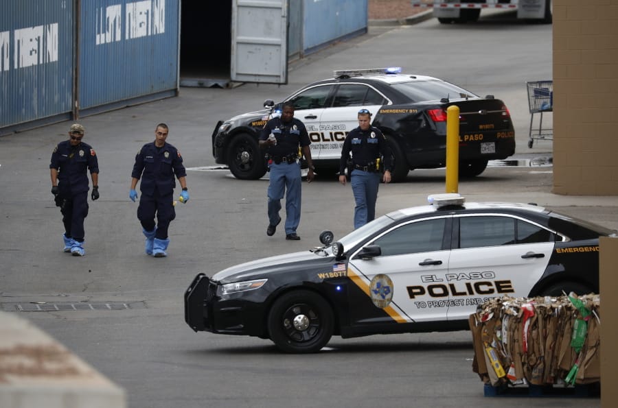 FILE - In this Aug. 6, 2019, file photo, police officers walk behind a Walmart at the scene of a mass shooting at a shopping complex in El Paso, Texas. Patrick Crusius, 21, was indicted Thursday, Sept. 12, 2019, for capital murder in connection with the Aug. 3 mass shooting that left 22 dead. He is jailed without bond.