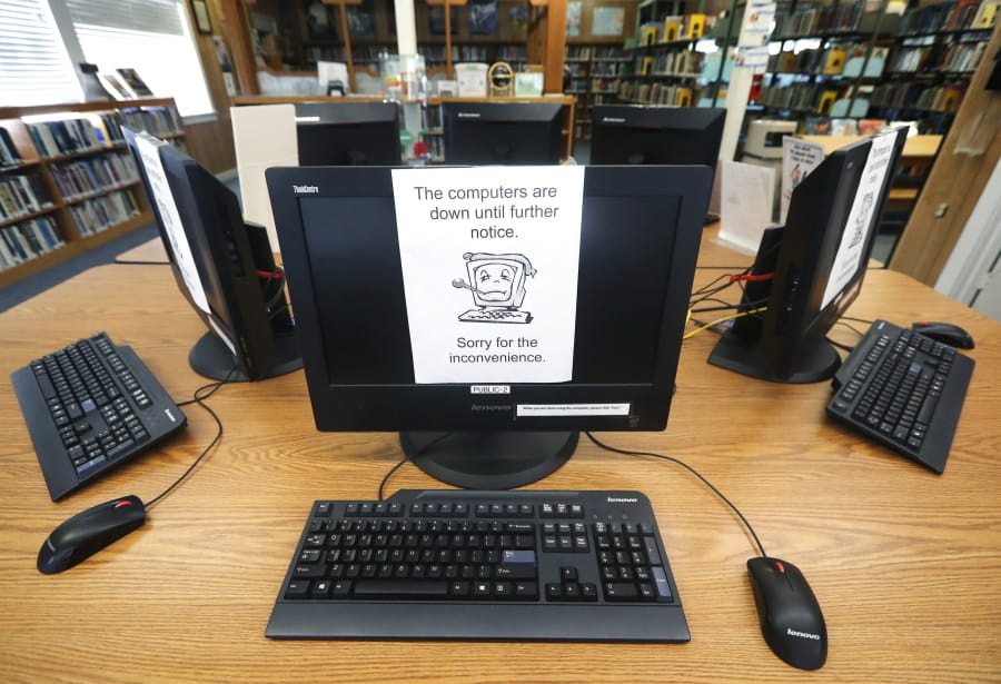 FILE - In this Aug. 22, 2019, file photo, signs on a bank of computers tell visitors that the machines are not working at the public library in Wilmer, Texas. Some cybersecurity professionals are concerned that insurance policies designed to limit the damage of ransomware attacks might actually be encouraging hackers. Twenty-two local governments in Texas were hit in August.