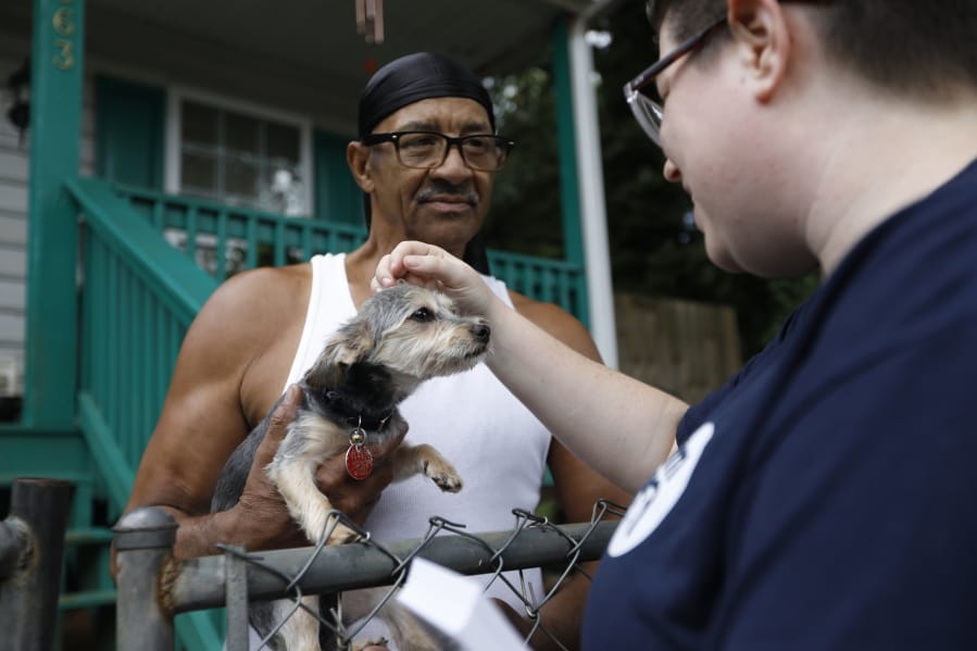 Sylvanus Jackson, left, brings his dog out to meet Lizzy Trawick, a coordinator for LifeLine Animal Project&#039;s Pets for Life program in Atlanta. Trawick visited Jackson&#039;s neighborhood to complete door-to-door outreach for the program, which provides free resources to pet owners in need. Jackson said he has benefited from the program.