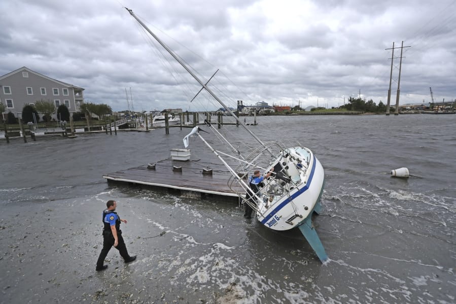 Beaufort Police Officer Curtis Resor, left, and Sgt. Micheal Stepehens check a sailboat for occupants in Beaufort, N.C. after Hurricane Dorian passed the North Carolina coast on Friday, Sept. 6, 2019. Dorian howled over North Carolina’s Outer Banks on Friday — a much weaker but still dangerous version of the storm that wreaked havoc in the Bahamas — flooding homes in the low-lying ribbon of islands and throwing a scare into year-round residents who tried to tough it out.