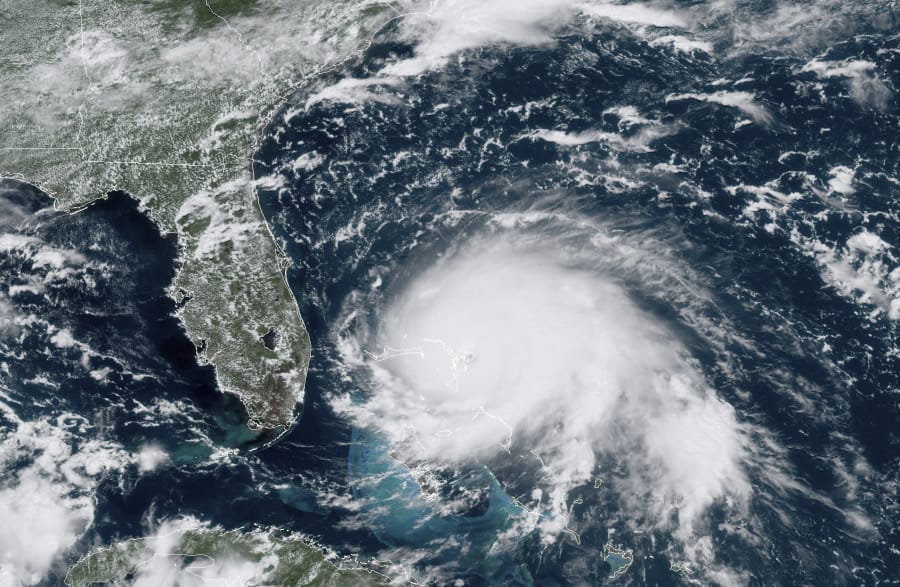 This GOES-16 satellite image taken Sunday, Sept. 1, 2019, at 17:00 UTC and provided by National Oceanic and Atmospheric Administration (NOAA), shows Hurricane Dorian, right, churning over the Atlantic Ocean. Hurricane Dorian struck the northern Bahamas on Sunday as a catastrophic Category 5 storm, its 185 mph winds ripping off roofs and tearing down power lines as hundreds hunkered in schools, churches and other shelters.