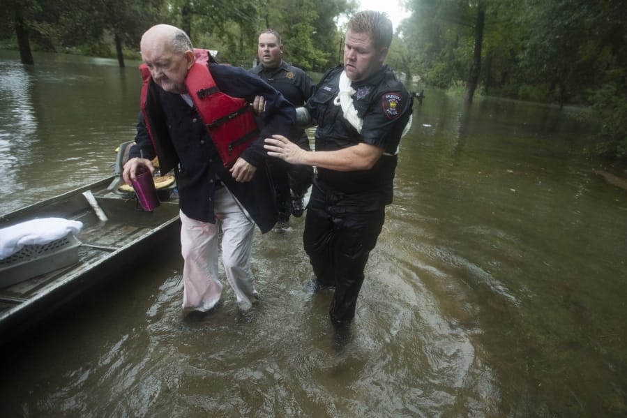 Fred Stewart, left, is helped to high ground by Splendora Police officer Mike Jones after he was rescued from his flooded neighborhood as rains from Tropical Depression Imelda inundated the area, Thursday, Sept. 19, 2019, in Splendora, Texas.