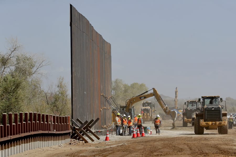 Government contractors erect a section of Pentagon-funded border wall Tuesday along the Colorado River in Yuma, Ariz. The 30-foot high wall replaces a five-mile section of Normandy barrier and post-n-beam fencing, shown at left, along the border that separates Mexico and the United States.