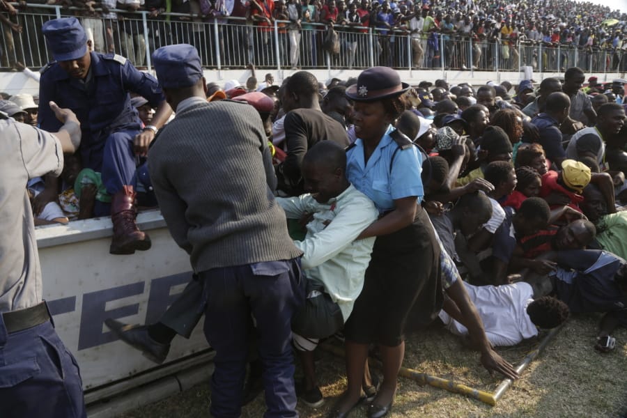 Injured mourners are helped after a stampede when mourners pushed and shoved after the arrival of the coffin carrying former President Robert Mugabe at the Rufaro Stadium in Harare, Thursday, Sept. 12, 2019 where Mugabe will lie in state for a public viewing. Mugabe, the founder leader, made his final journey back to the country Wednesday amid continuing controversy over where he will be buried.