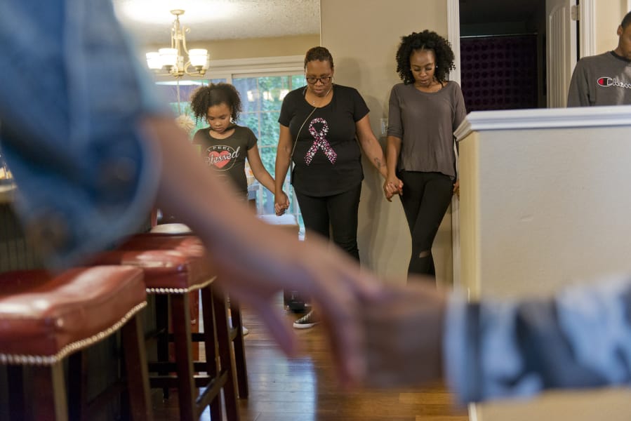 Family friend Zahira Cooper, 9, from left, Zsaneen Kennedy and her daughter LaQuay Kennedy pray before dinner. The family often gathers for dinner. Kennedy said she is concerned about her daughters getting breast cancer, which runs in the family.