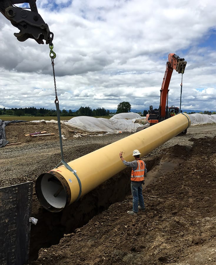 Workers lower a pipe into a trench as part of Oregon&#039;s Willamette Water Supply Program, which will add a new water filtration plant and more than 30 miles of pipeline to accommodate future population growth in the Hillsboro and Tualatin Valley Water District area.
