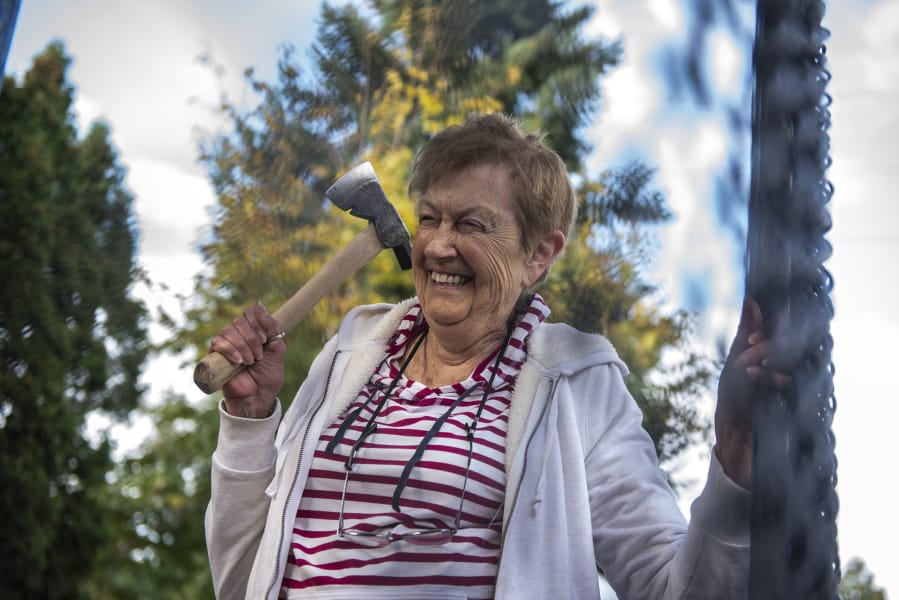 Jo Borwick, 84, laughs while taking aim during an ax throwing event at Highgate Senior Living. Many of the seniors held onto the walls of the mobile ax throwing unit for balance as they threw.