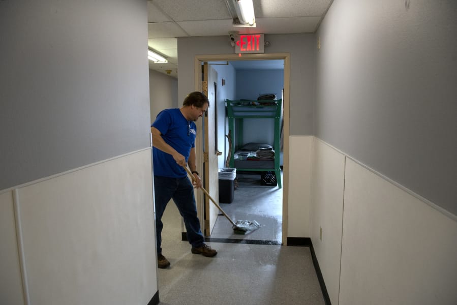 Dean Cardiff, engagement specialist with Share House, cleans the newly replaced floors Monday afternoon shortly before residents were set to return to the shelter. The men's homeless shelter reopened Monday evening after nine weeks of being closed to repair fire and water damage.