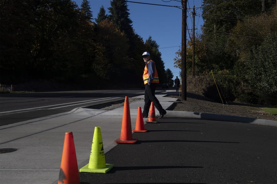 Les MacDonald, the incoming deputy public works director for Clark County, examines a section of new sidewalk along the east side of Highway 99 following a short sidewalk celebration event Thursday afternoon.