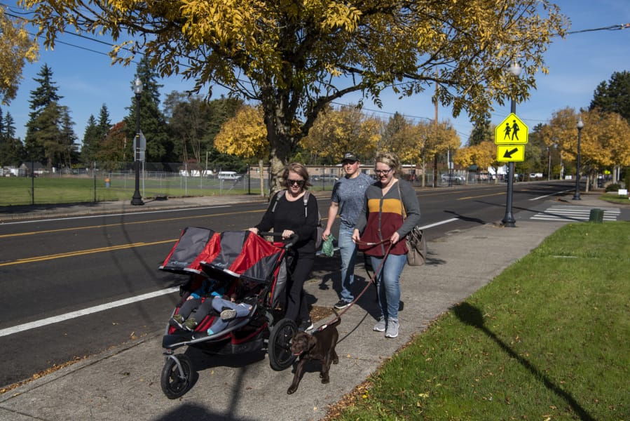 Emily Gillingham, from left, of La Center, and Mitchell Stivers and Alexis Gillingham, both of Battle Ground, take an afternoon stroll together with Gillingham's kids and Stivers and Alexis Gillingham's new puppy along North Parkway Avenue in Battle Ground on Friday.