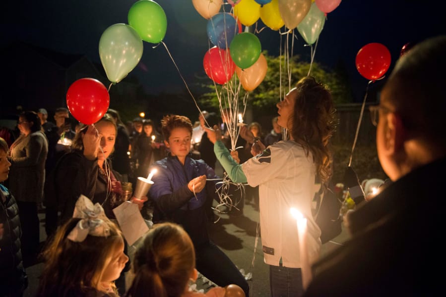 Shannon Melby hands out balloons during a candlelight vigil for 10-year-old Damien Trick on Saturday night, at the intersection where Damien was stuck by a vehicle and killed while riding his bike on Tuesday morning.