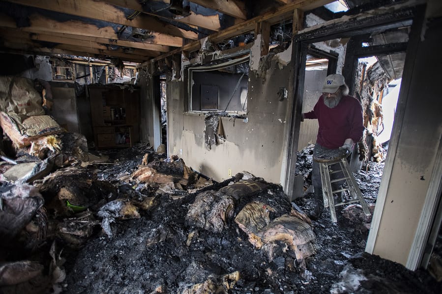 Mark Evans of Washougal removes charred items from the interior of Wanda Walker LMP, one of four businesses damaged by a fire early Sunday morning.