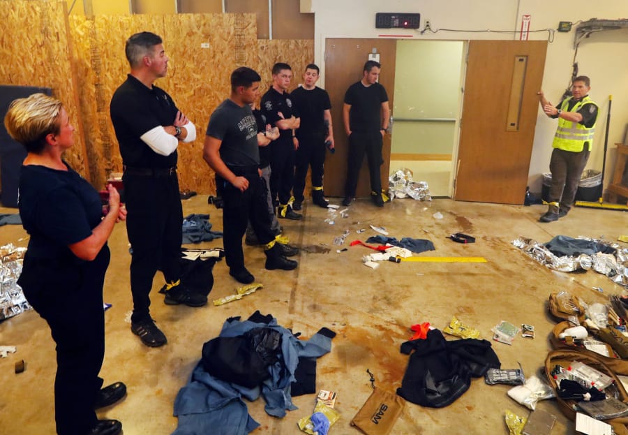 The floor is littered with first-aid equipment wrappers Sept. 26 during a debriefing with SWAT EMT Marshall Coolidge, right, at an advanced trauma-care class at the Seattle Police Department in Seattle. The scenario is that police are first responders to an explosion which has injured many.