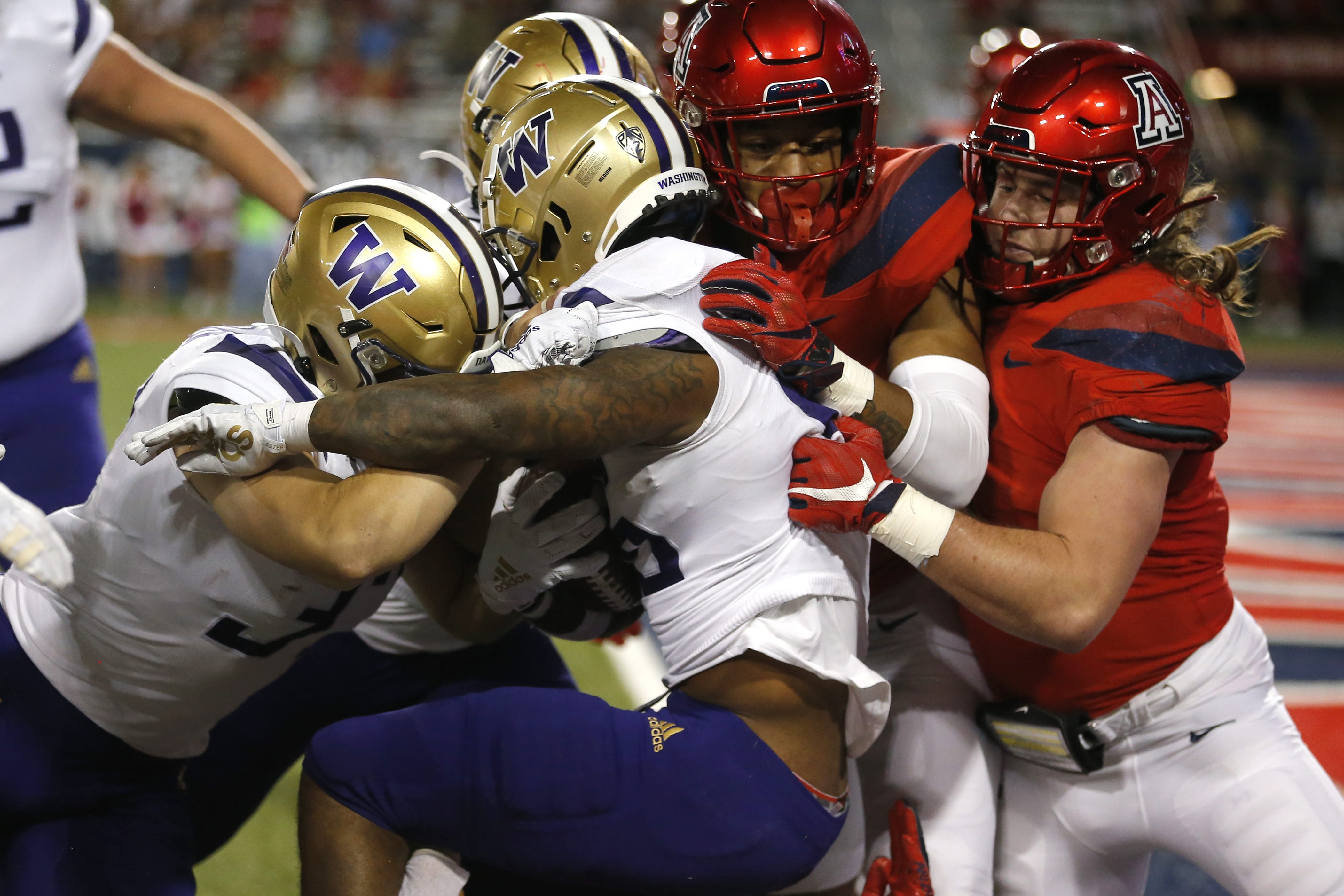 Washington running back Salvon Ahmed, middle, gets pushed into the endzone for a touchdown against Washington in the second half during an NCAA college football game, Saturday, Oct. 12, 2019, in Tucson, Ariz.