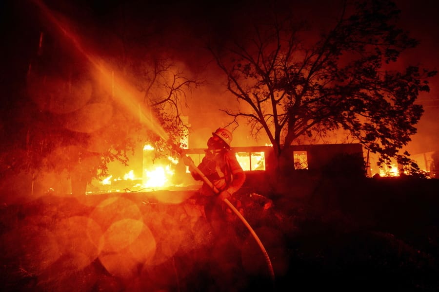 A firefighter sprays water as flames from the Hillside fire consume a residence in San Bernardino, Calif., on Thursday, Oct. 31, 2019. The blaze, which ignited during red flag fire danger warnings, destroyed multiple residences.