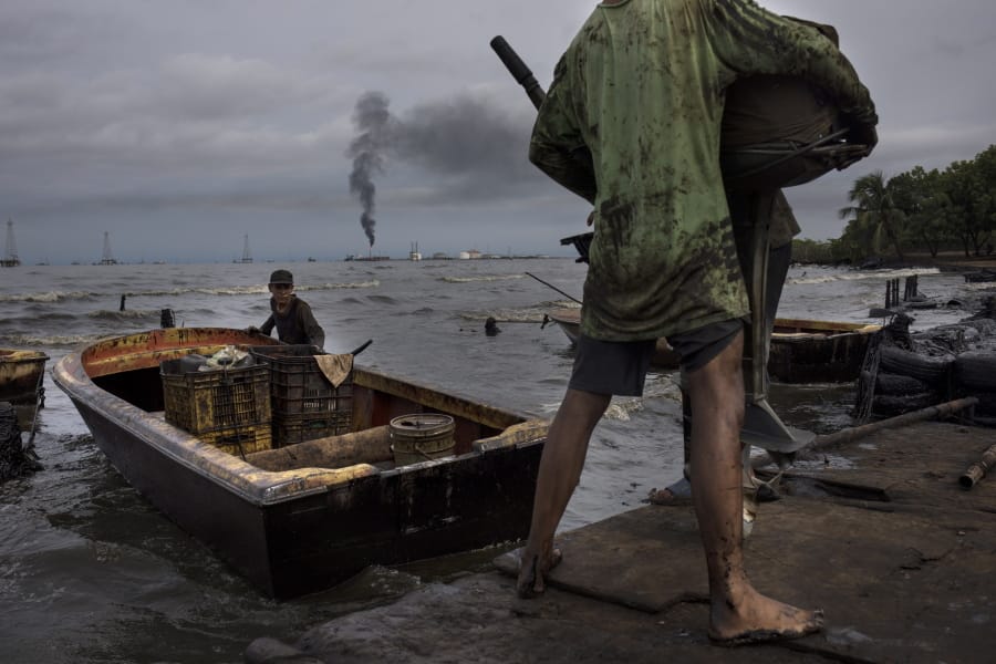 Fishermen covered in oil get their boat ready for fishing July 9 on Lake Maracaibo near La Salina crude oil shipping terminal in Cabimas, Venezuela.