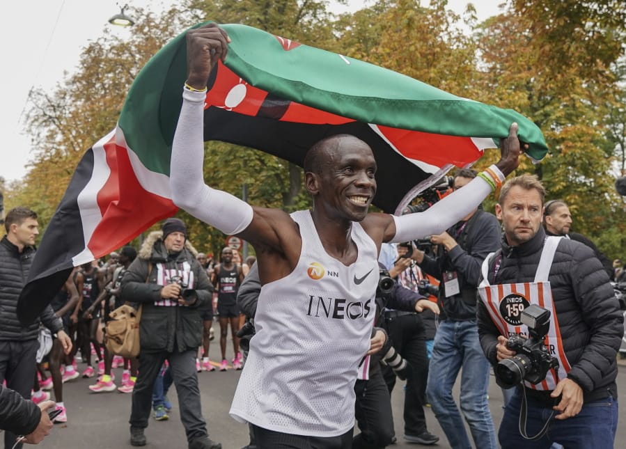 Eliud Kipchoge celebrates with the Kenyan flag after breaking the historic two hour barrier for a marathon in Vienna, Saturday, Oct. 12, 2019. Eliud Kipchoge has become the first athlete to run a marathon in less than two hours, although it will not count as a world record. The Olympic champion and world record holder from Kenya clocked 1 hour, 59 minutes and 40 seconds Saturday at the INEOS 1:59 Challenge, an event set up for the attempt.