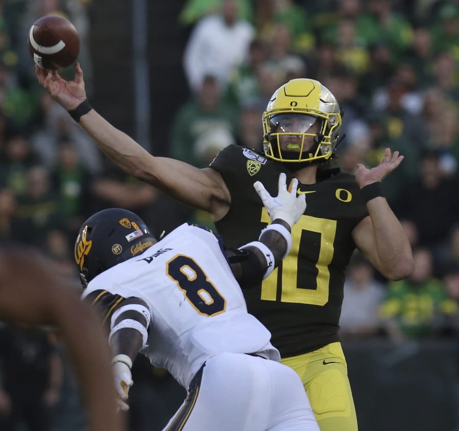 Oregon quarterback Justin Herbert, right, passes under pressure from California&#039;s Kuony Deng during the second quarter of an NCAA college football game Saturday, Oct.. 5, 2019, in Eugene, Ore.