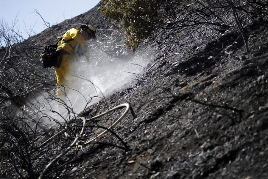Anthony Ayala with the South Placer Fire Dept. hoses down hot spots in the aftermath of a wildfire Saturday, Oct. 12, 2019, in Porter Ranch, Calif.