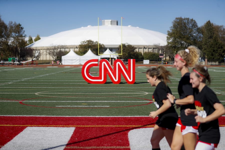 Student athletes pass a CNN sign on an athletic field outside the Clements Recreation Center where the CNN/New York Times will host the Democratic presidential primary debate at Otterbein University, Monday, Oct. 14, 2019, in Westerville, Ohio.