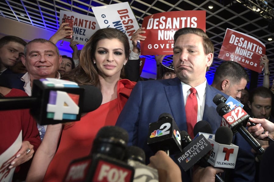 FILE- In this Nov. 6, 2018 file photo, Florida Govenor-elect Ron DeSantis, right, answers questions from reporters, with his wife Casey, after being declared the winner of the Florida gubernatorial race at an election party, in Orlando, Fla. Standing behind Casey DeSantis is Lev Parnas. Parnas and his associate Igor Furman are facing federal charges in connection to efforts by President Donald Trump&#039;s lawyer, Rudy Giuliani, to launch a Ukrainian corruption investigation agains Joe Biden and his son, Hunter. (AP Photo/Phelan M.