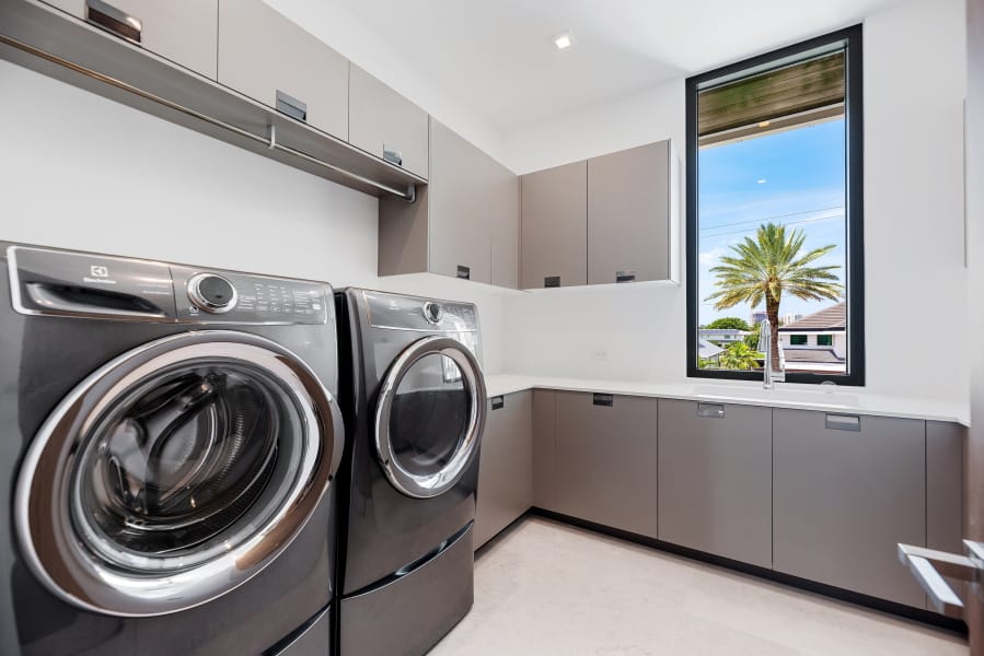 This photo provided by interior designer Raquel Mothe of Mothe Design shows a laundry room designed by Mothe in Fort Lauderdale, Fla. This laundry room includes plenty of storage with cabinets by Ornare, as well as recessed ceiling lighting and natural light, creating a space that&#039;s welcoming and also functional.