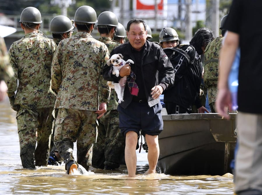 An evacuee with a dog is rescued by Self-Defense force members as the city is hit by Typhoon Hagibis, in Motomiya, Fukushima prefecture, northern Japan, Sunday, Oct. 13, 2019.