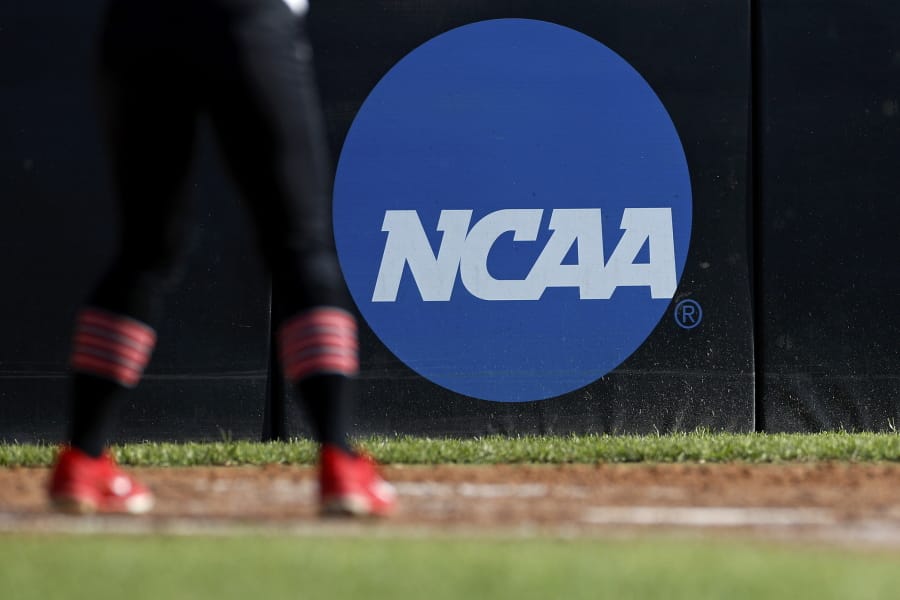 FILE - In this April 19, 2019, file photo, an athlete stands near a NCAA logo during a softball game in Beaumont, Texas. The NCAA is poised to take a significant step toward allowing college athletes to earn money without violating amateurism rules. The Board of Governors will be briefed Tuesday, Oct. 29 by administrators who have been examining whether it would be feasible to allow college athletes to profit of their names, images and likenesses. A California law set to take effect in 2023 would make it illegal for NCAA schools in the state to prevent athletes from signing personal endorsement deals. (AP Photo/Aaron M.