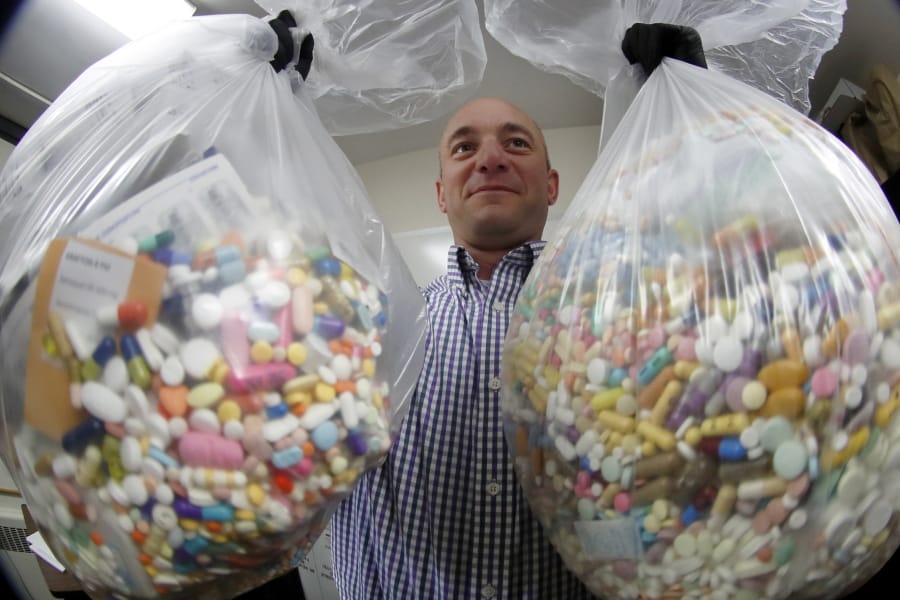 FILE - In this Wednesday, Sept. 11, 2019, file photo, narcotics detective Ben Hill, with the Barberton Police Department, shows two bags of medications that are are stored in their headquarters and slated for destruction in Barberton, Ohio. Jury selection is set to begin Wednesday, Oct. 16, 2019, in the first federal trial over the nation&#039;s opioid epidemic.