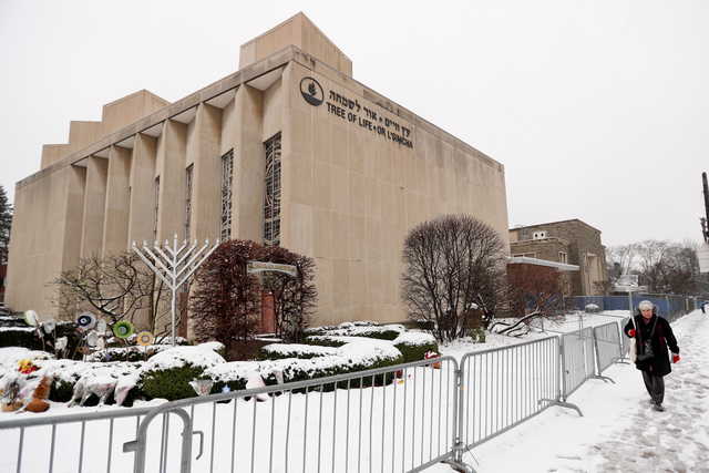 In this  Monday, Feb. 11, 2019 file photo, a woman passes by the Tree of Life Synagogue in Pittsburgh’s Squirrel Hill neighborhood. Leaders of the synagogue where worshippers were fatally shot last year want to rebuild and renovate the building, turning it into what they hope will be a symbol against hatred and “the center for Jewish life in the United States.” On Thursday, Oct. 17, 2019 they outlined their vision for the Tree of Life building, where three congregations — Tree of Life, Dor Hadash and New Light — had gathered Oct. 27 when a gunman opened fire, killing 11 and wounding seven..
