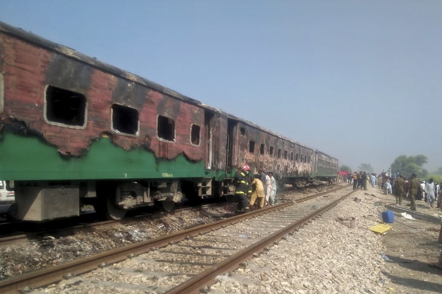 Pakistani officials examine a train damaged by a fire in Liaquatpur, Pakistan, Thursday, Oct. 31, 2019.