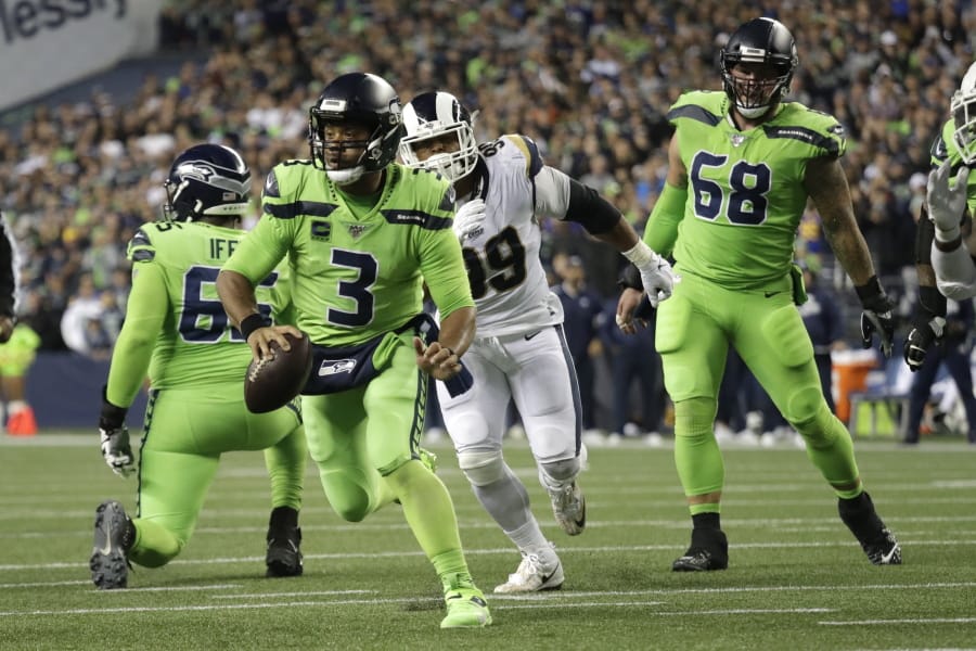 Seattle Seahawks quarterback Russell Wilson (3) scrambles before making a short pass to running back Chris Carson for a touchdown against the Los Angeles Rams during the second half of an NFL football game Thursday, Oct. 3, 2019, in Seattle.