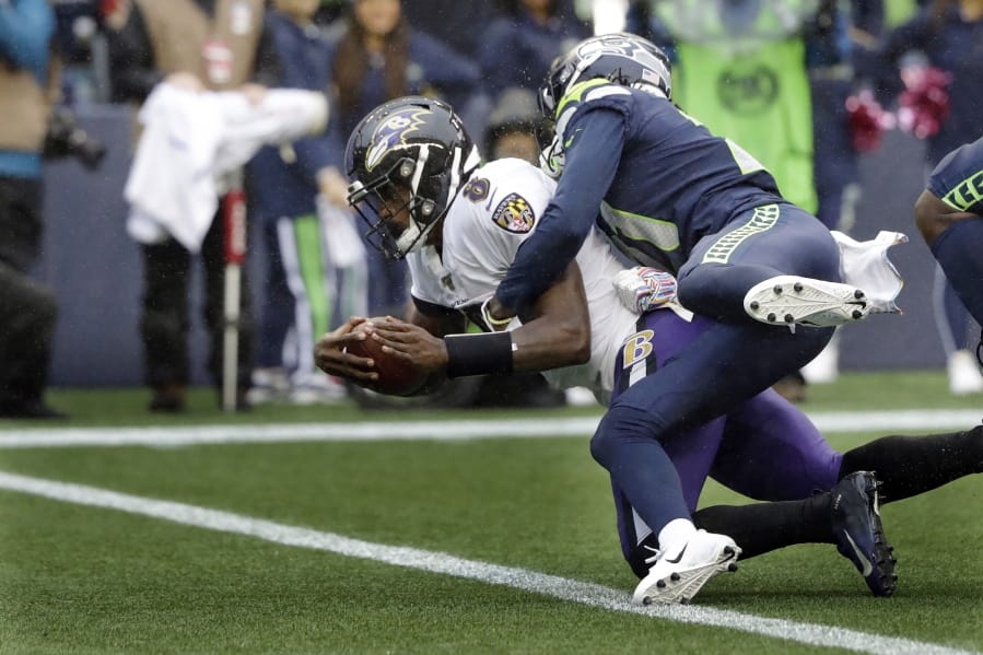 Baltimore Ravens quarterback Lamar Jackson (8) is hit by Seattle Seahawks cornerback Tre Flowers while scoring a touchdown on a fourth-down keeper play during the second half of an NFL football game, Sunday, Oct. 20, 2019, in Seattle.