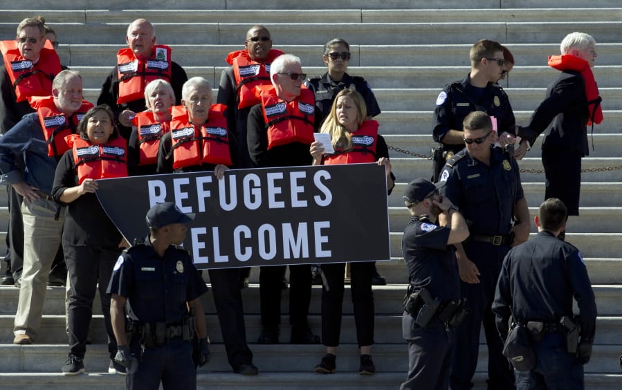 Faith leaders and members of human rights groups wear life vests symbolizing the lifesaving program are arrested by U.S. Capitol police Tuesday during a protest calling congress not to end the refugee resettlement program, at the steps of the U.S. Capitol in Washington.