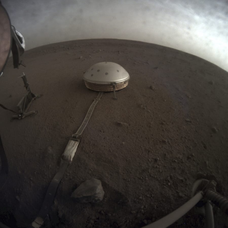 The InSight lander&#039;s dome-covered seismometer, known as SEIS, is seen on Mars in this April 25 photo. On Oct. 1, scientists released an audio sampling of marsquakes and other sounds recorded by the probe.