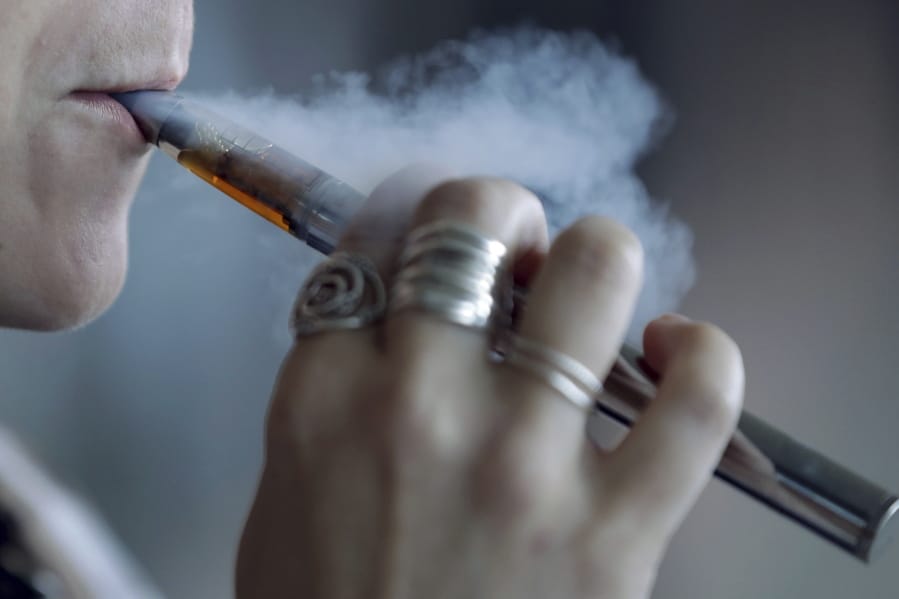 A woman using an electronic cigarette exhales a puff of smoke.