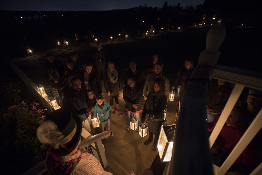 Volunteer Reggie Coats, bottom in hat, speaks to a group about to begin a lantern tour while other visitors make their way around the Fort Vancouver National Historic Site with their lanterns, one evening in October 2017.