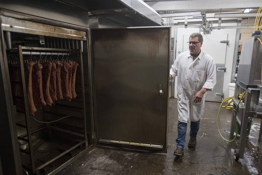 Peter Kurfurst, manager and co-owner of Butcher Boys, checks on bacon in a smoker on Tuesday afternoon. The shop added its first indoor smokehouse in 1988, and the lineup has expanded to three. The modern smokehouses are computerized, allowing Kurfurst and other staff to keep an eye on things remotely.