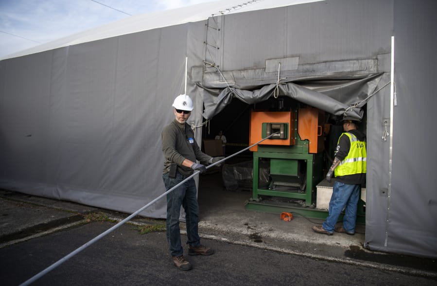 Investment Recovery Center foreman David Boggs, left, and material handler Beau Benavides, right, feed old transmission cable into &quot;the chopper,&quot; a machine that separates aluminum and steel, Thursday afternoon at the Bonneville Power Administration&#039;s Ross Complex in Vancouver.