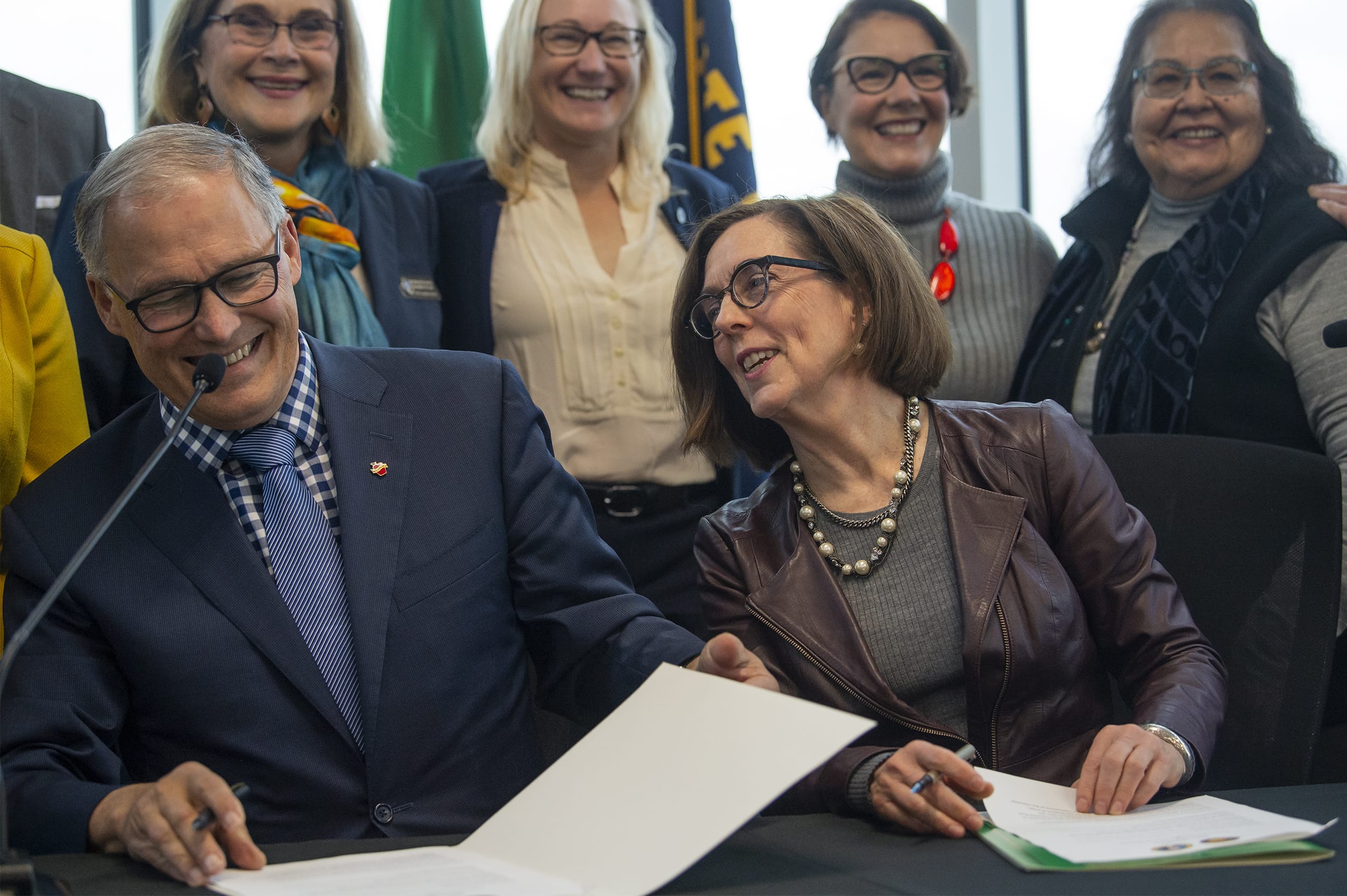 Washington Gov. Jay Inslee, left, and Oregon Gov. Kate Brown celebrate with supporters after signing a memorandum of intent to replace the Interstate 5 bridge at the Murdock Charitable Trust on Monday morning, Nov. 18, 2019.